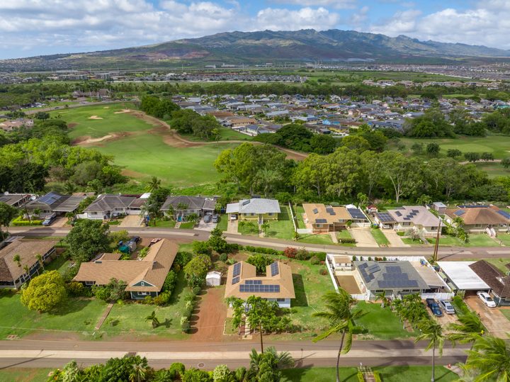 Aerial view of ʻEwa Beach homes beside a golf course with the Waiʻanae Range behind