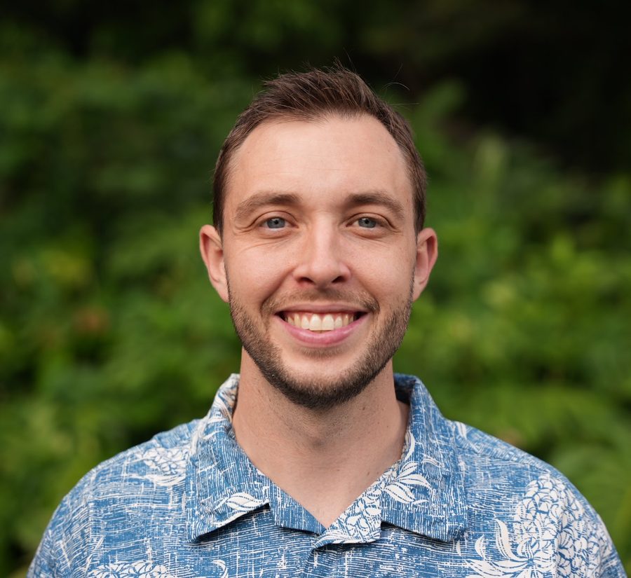 Matthew Ball, REALTOR®, smiling in a blue aloha shirt in front of green leaves